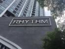 Exterior view of a tall residential building with the 'Rhythm' sign