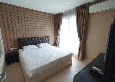 Modern bedroom with double bed, padded headboard, window with curtains, and air conditioning unit