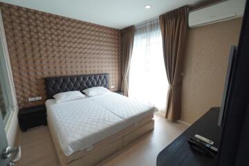 Modern bedroom with double bed, padded headboard, window with curtains, and air conditioning unit