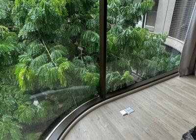 Living area with large curved glass windows and view of greenery