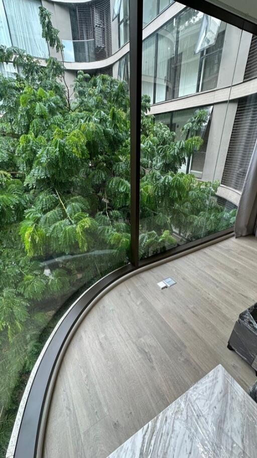 Living area with large curved glass windows and view of greenery