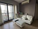 Living room with a couch, small coffee table, air conditioning, and a balcony view