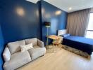 Modern bedroom with blue walls, bed, sofa, and desk