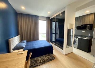 Well-lit modern bedroom with a workspace and a view into the kitchen