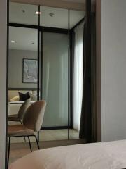 Modern bedroom with mirrored sliding doors and view of bed and chair