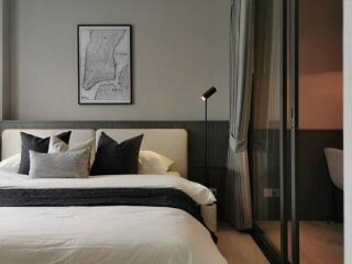 Modern bedroom with bed, pillows, bedside lamp, and wall art