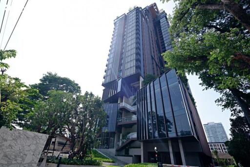 Modern high-rise residential building with large glass windows surrounded by trees