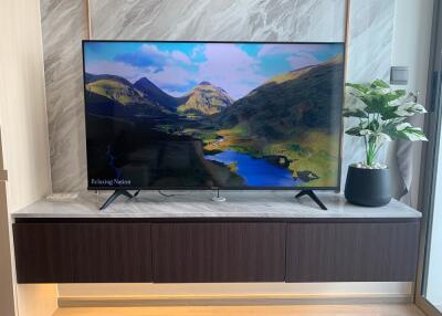 Modern living room with a wall-mounted TV and a decorative plant on a floating cabinet