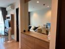 Modern living room with a large mirror, wall-mounted TV, and air conditioning unit.