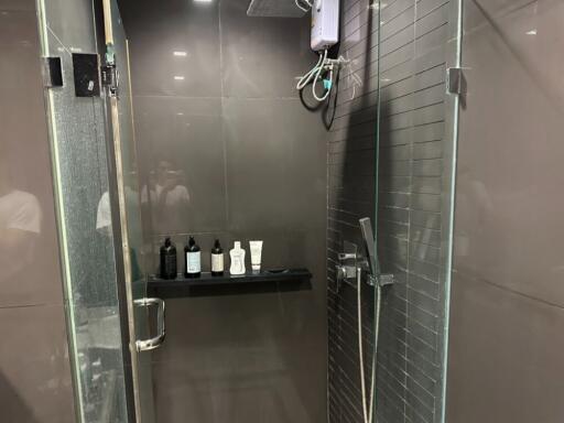 Modern bathroom with glass shower enclosure and wall-mounted toiletries shelf