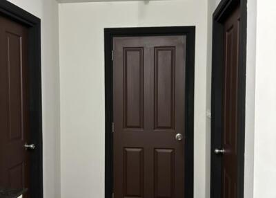 Hallway with three brown doors and wooden flooring