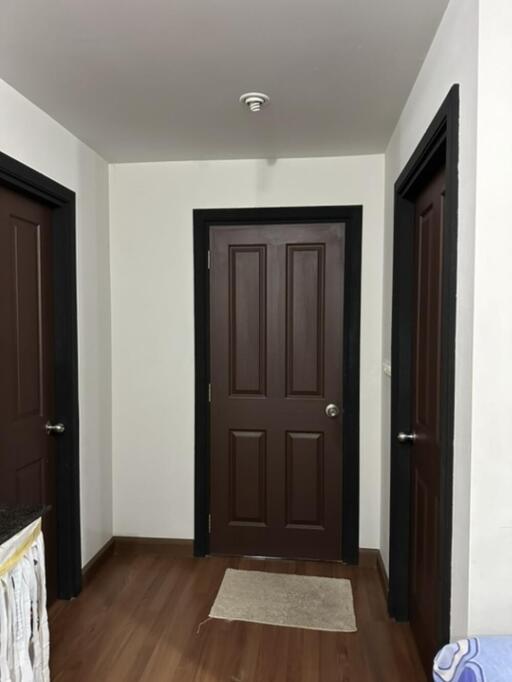 Hallway with three brown doors and wooden flooring