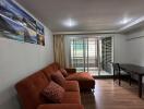 Living room with orange sofa, dining table, and sliding doors to balcony