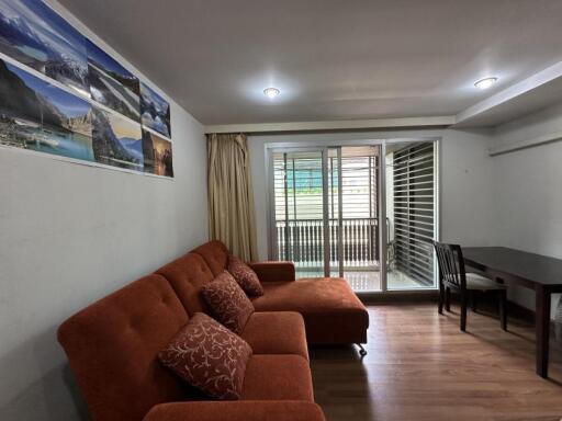 Living room with orange sofa, dining table, and sliding doors to balcony