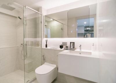 Modern bathroom with glass shower, toilet, and vanity area