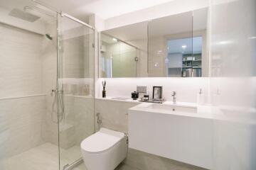 Modern bathroom with glass shower, toilet, and vanity area