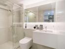 Modern bathroom with glass shower, toilet, and vanity area