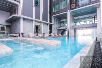 Swimming pool area of a modern residential building with lounge chairs.