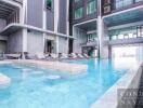 Swimming pool area of a modern residential building with lounge chairs.