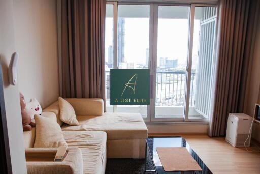 Cozy living room with a beige sofa, large windows, and a city view