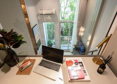 Modern home office with a computer, books, and a window view