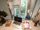 Modern home office with a computer, books, and a window view