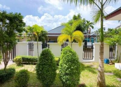 A lush garden area with various trees and plants, and a view of neighboring houses.