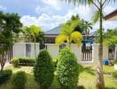 A lush garden area with various trees and plants, and a view of neighboring houses.