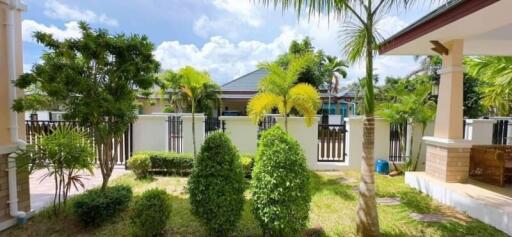 A lush garden area with various trees and plants, and a view of neighboring houses.