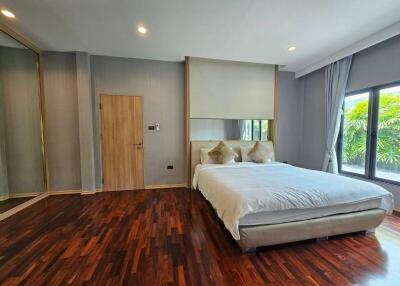 Modern bedroom with wooden flooring and large window