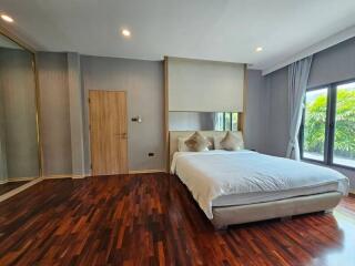 Modern bedroom with wooden flooring and large window