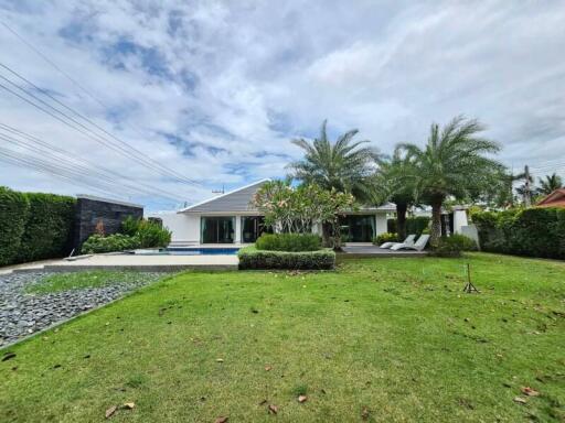 Spacious garden with lush greenery, pool, and seating area