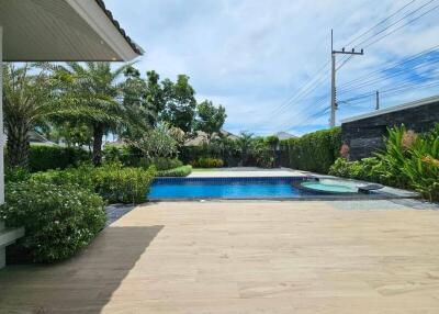 Outdoor pool area with wooden deck and landscaping