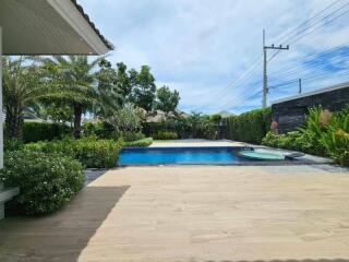 Outdoor pool area with wooden deck and landscaping