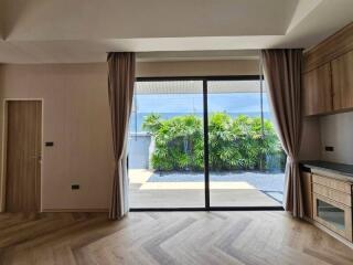 Living room with large glass doors, curtains, and a view of a garden