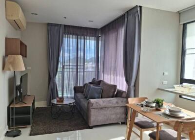 Comfortable living room with grey sofa, dining table, and large windows