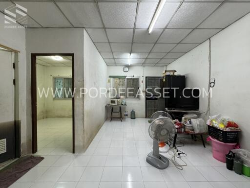 Spacious living area with tiled floor, television, and basic furnishings.