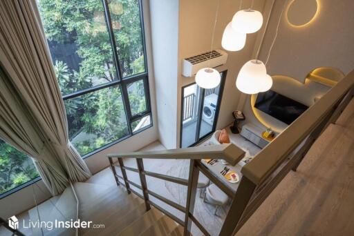 Modern living room with large windows, a cozy seating area, and stylish lighting fixtures