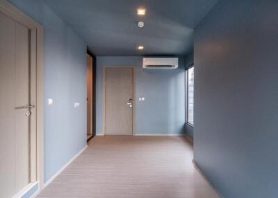 Spacious empty room with blue walls and wooden flooring.