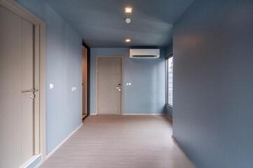 Spacious empty room with blue walls and wooden flooring.