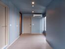 Spacious empty room with blue walls and wooden flooring.