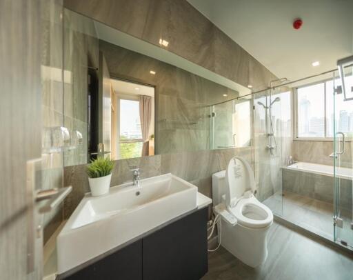 Modern bathroom with glass shower, bathtub, and large mirror