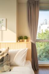 cozy bedroom with sunlight, plants, and a large window