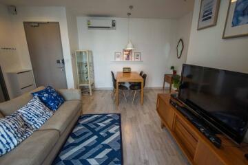 Living room with sofa, TV, dining table, and wall decor