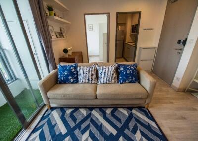 Cozy living room with a beige sofa, blue patterned cushions, and a geometric rug