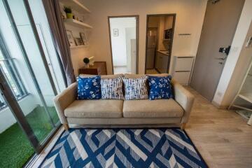 Cozy living room with a beige sofa, blue patterned cushions, and a geometric rug