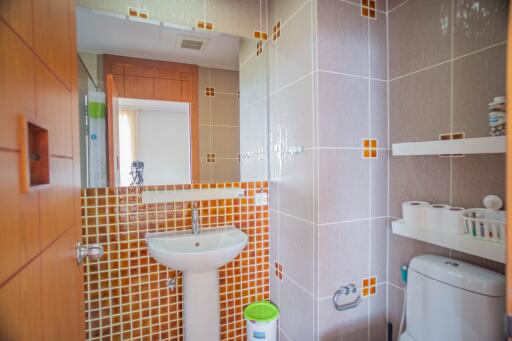 A modern bathroom with tiled walls and a white sink and toilet