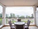 Outdoor balcony with a table and chairs facing a scenic view