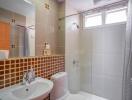 Modern bathroom with a large mirror, sink, toilet, and shower area