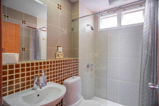 Modern bathroom with a large mirror, sink, toilet, and shower area